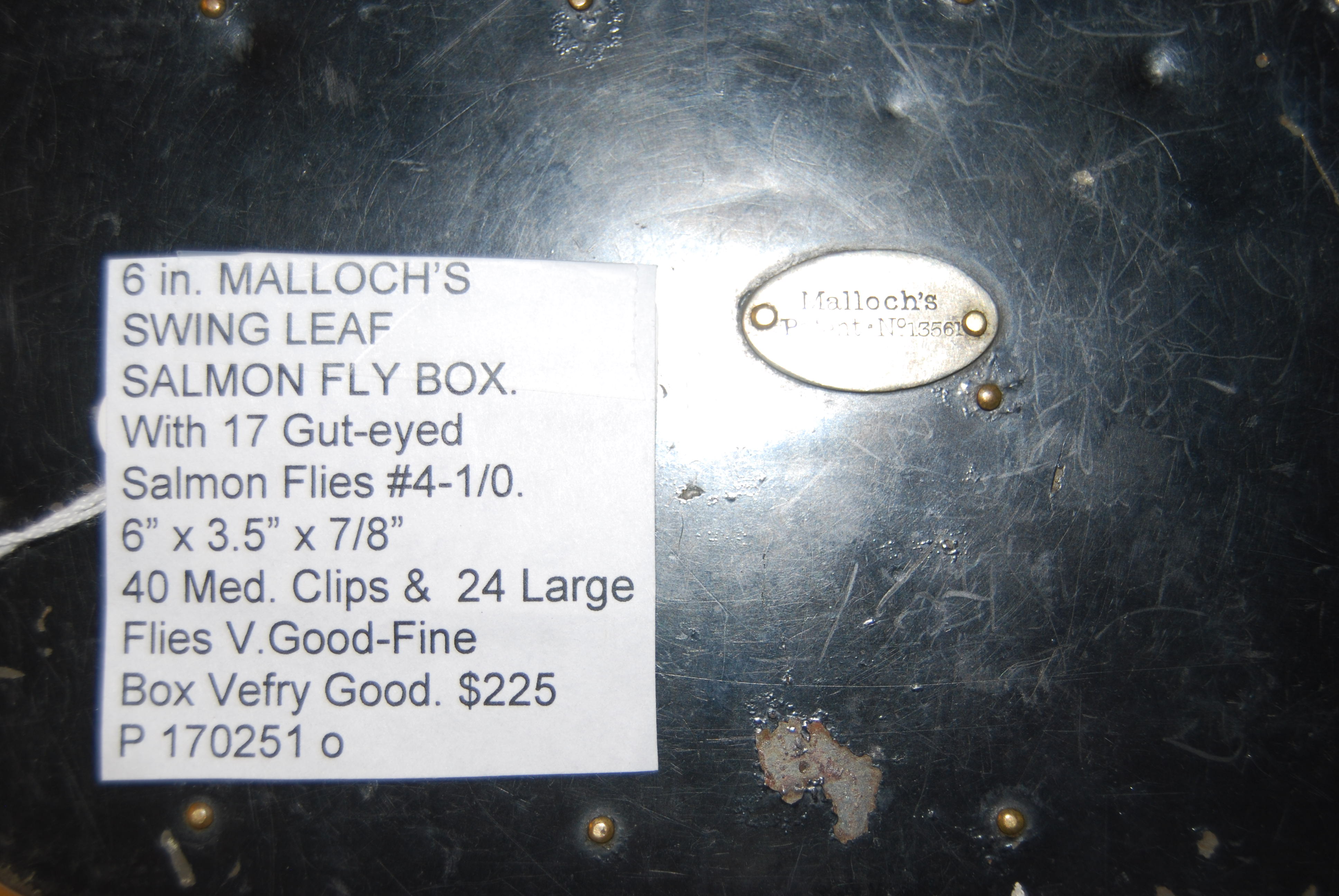 MALLOCH’S SWING LEAF SALMON FLY BOX. With 17 Gut-Eyed Salmon Flies, Full Dressed in Sizes #4 to 1/0. Marked on lid with Medallion: “Malloch’s/ Pat. No. 13561.” 6 in. x 3.5 in. x 7/8 in. With 40 Medium Clips & 24 Large Clips. Japanned tin with black exterior & ivory interior. Image for MALLOCH’S SWING LEAF SALMON FLY BOX. With 17 Gut-Eyed Salmon Flies, Full Dressed in Sizes #4 to 1/0. Marked on lid with Medallion: “Malloch’s/ Pat. No. 13561.” 6 in. x 3.5 in. x 7/8 in. With 40 Medium Clips & 24 Large Clips. Japanned tin with black exterior & ivory interior.